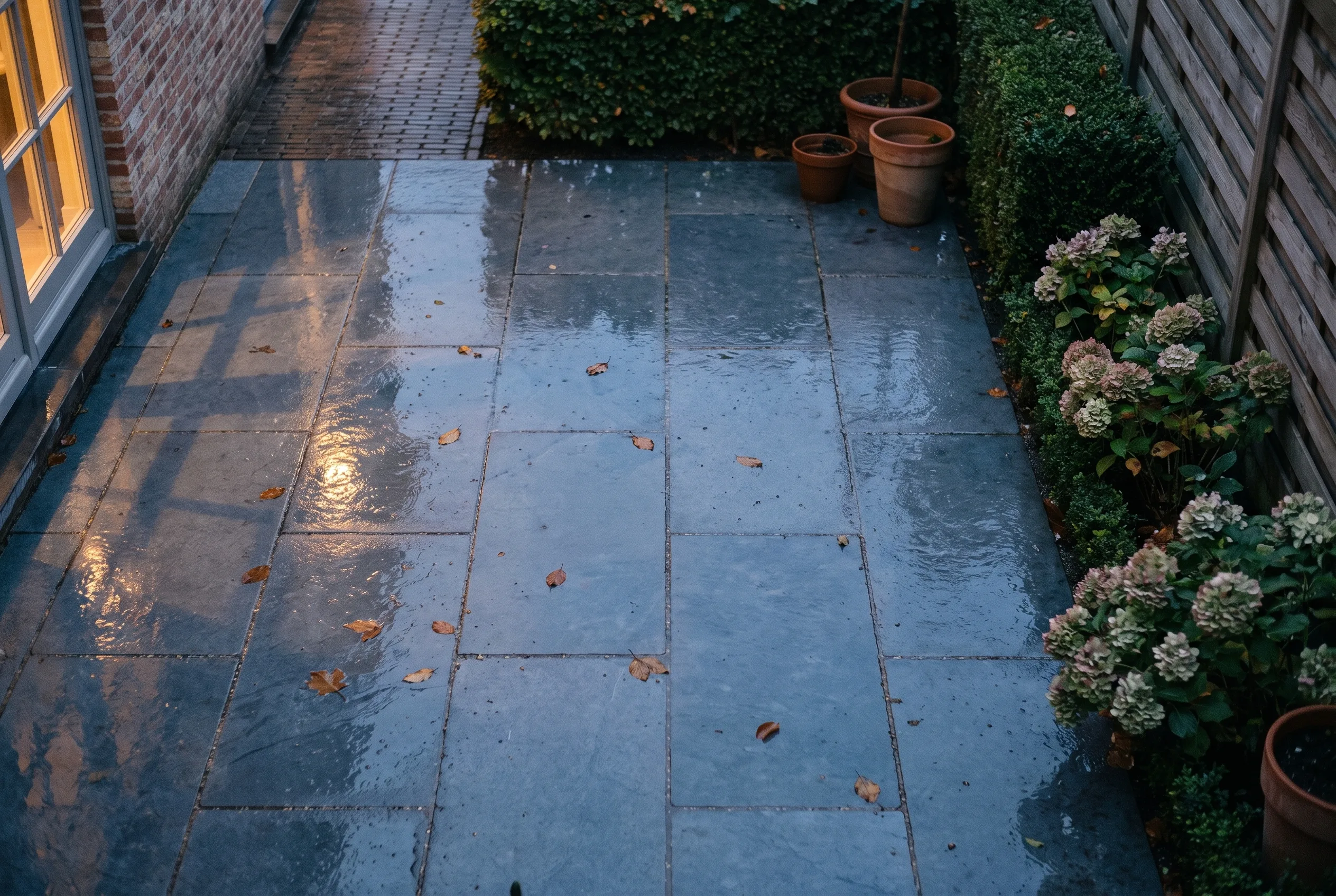 Natte terrastegels met warm weerkaatst licht.
